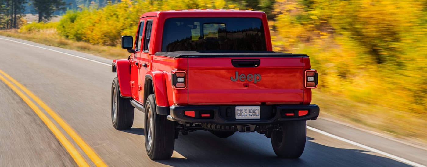 A red 2022 Jeep Gladiator is driving on an open road.