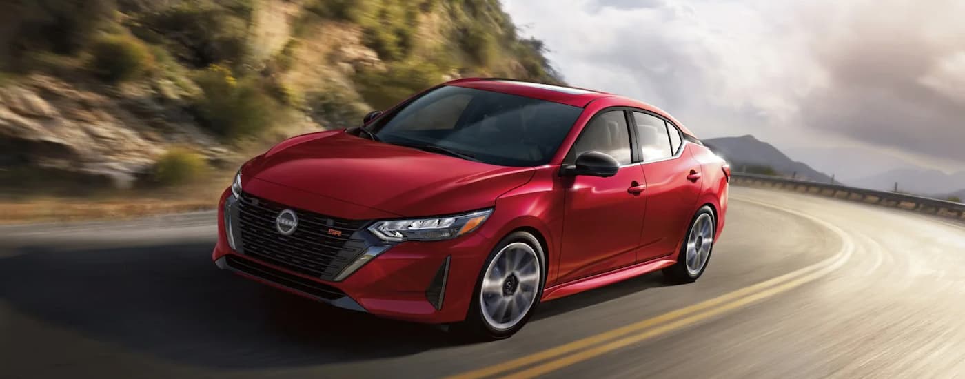 A red 2024 Nissan Sentra SR is driving on a winding highway road.