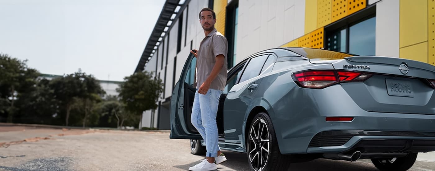 A man is getting out of the driver's side of a grey 2024 Nissan Sentra SR.