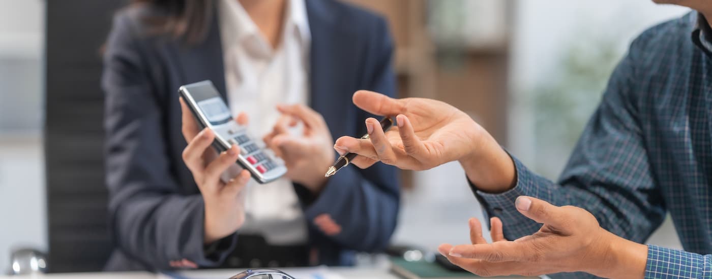 A saleswoman and customer are going over financing information at a car dealership.
