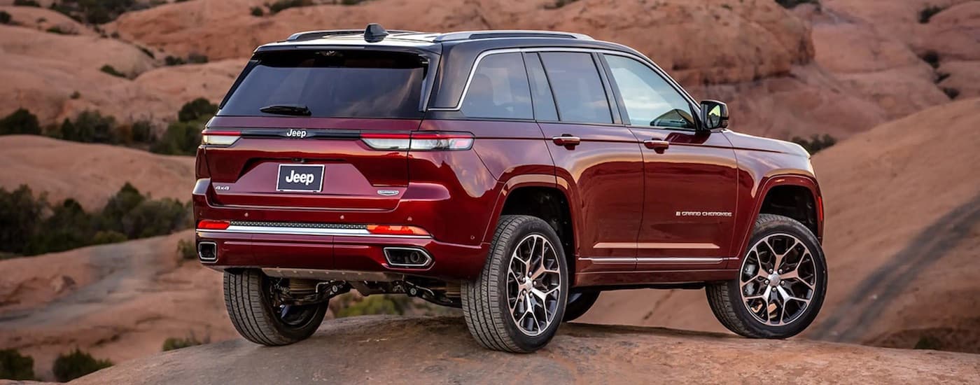 A red 2023 Jeep Grand Cherokee is shown from the rear at an angle after leaving a dealer that has a used Jeep for sale.