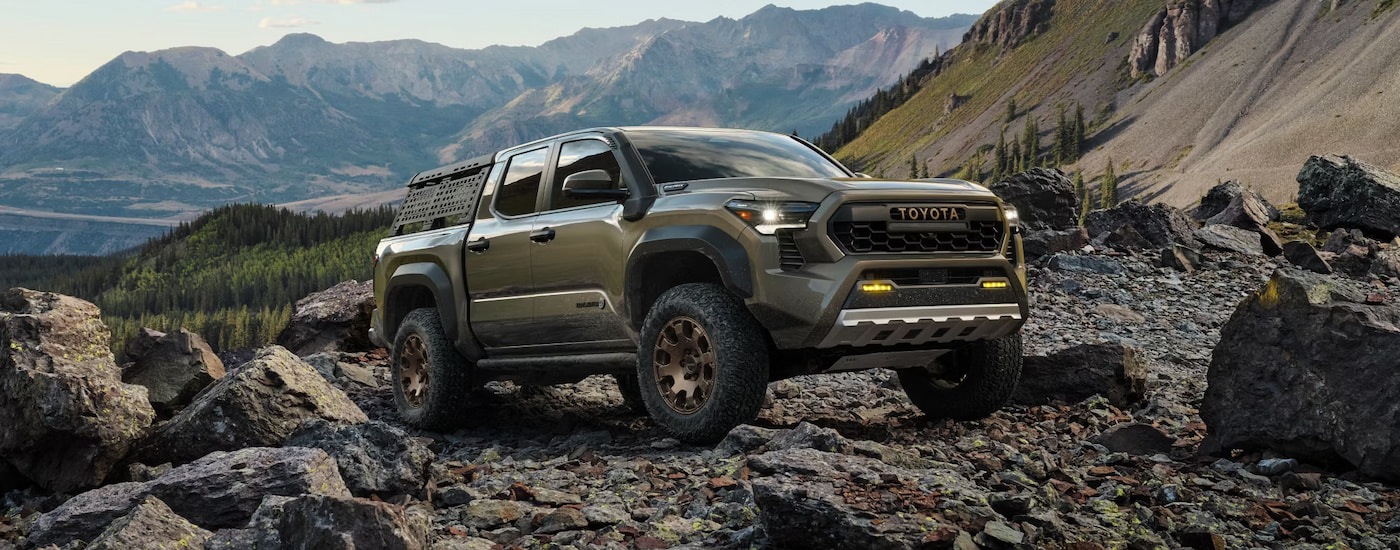 A grey-green 2024 Toyota Tacoma Trailhunter parked on a rocky mountain.