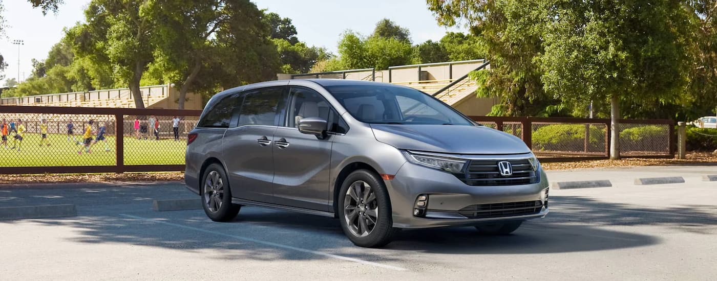 A silver 2022 Honda Odyssey Elite parked near a soccer field.