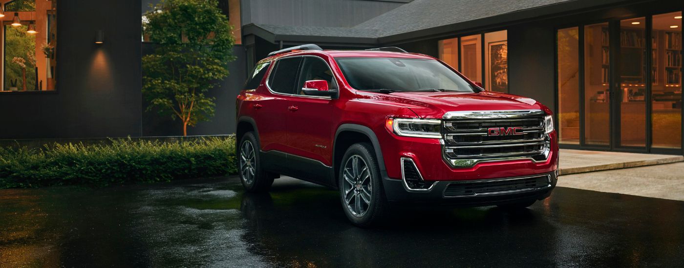 A red 2023 GMC Acadia SLT parked in a driveway.