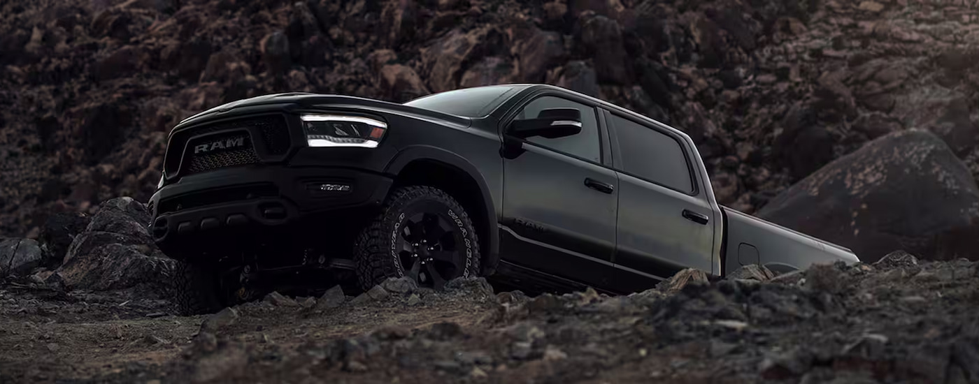 A black 2024 Ram 1500 Rebel GT Night Edition off-roading on a mountain.