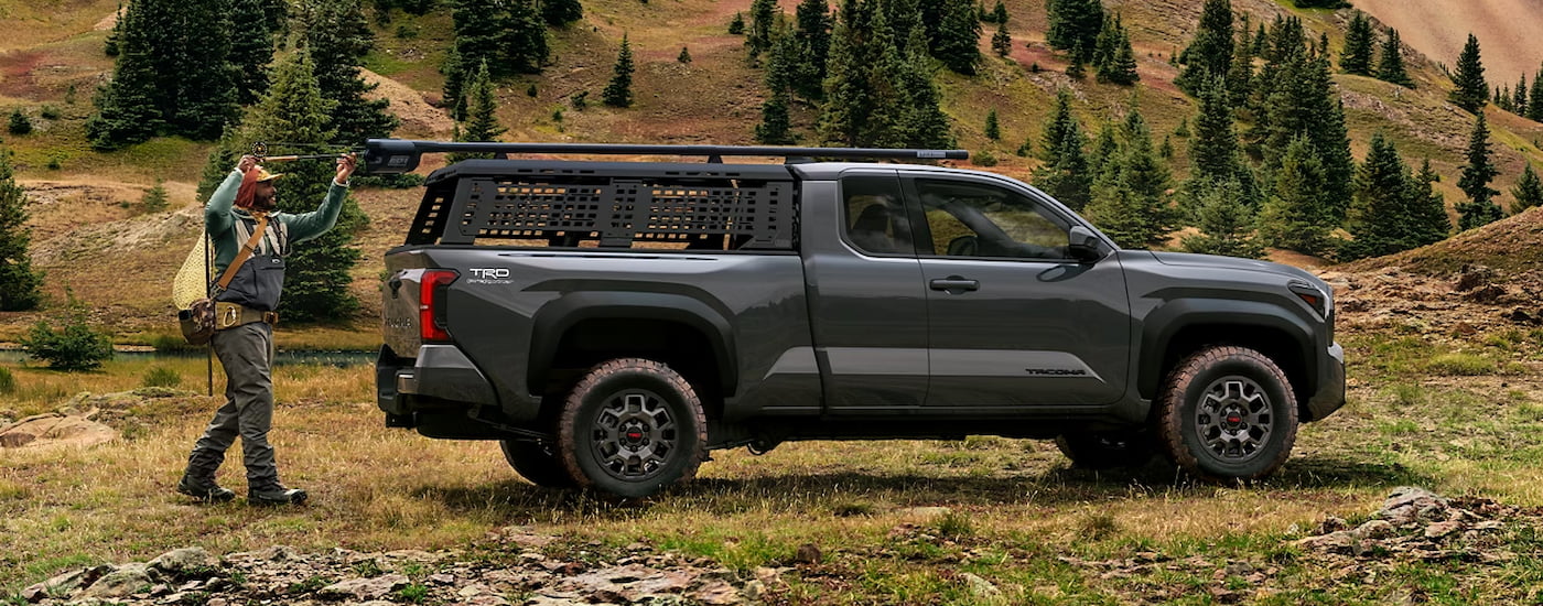 A hiker loading gear into the back of a grey 2024 Toyota Tacoma TRD PreRunner.