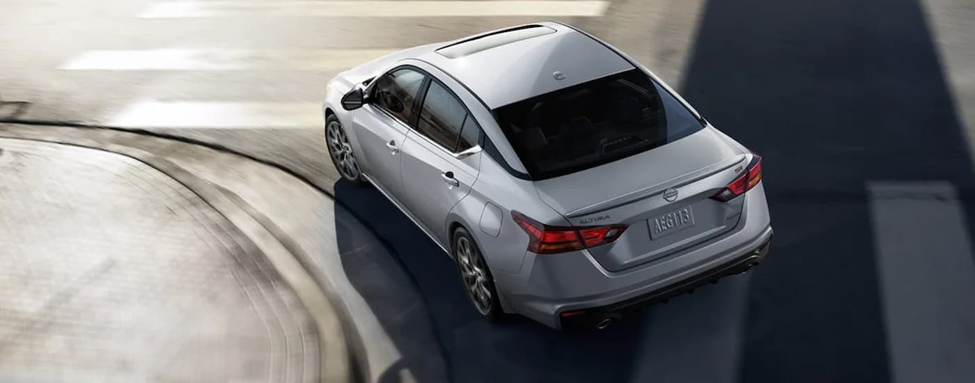 A silver 2024 Nissan Altima SR is taking a turn on a city street.