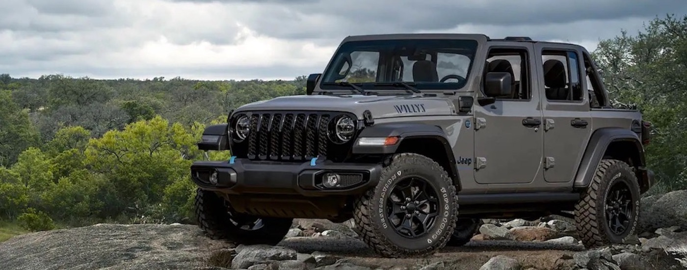 A grey 2023 Jeep Wrangler Unlimited Willys 4xe parked off-road.