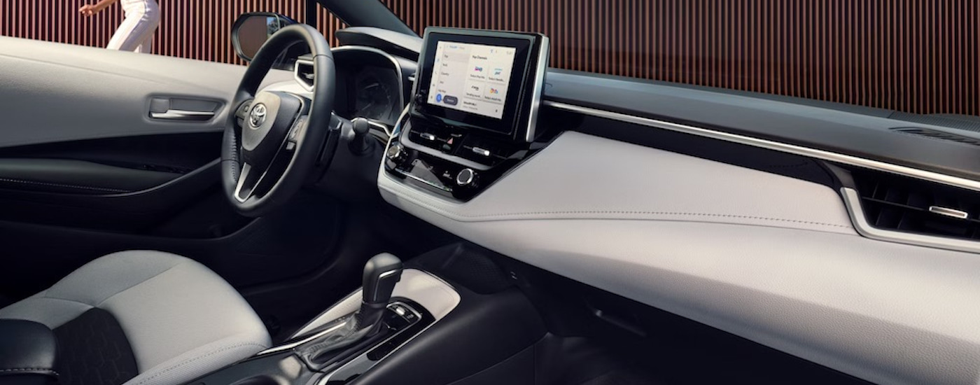 The white interior of a 2024 Toyota Corolla for sale is shown from the passenger seat.