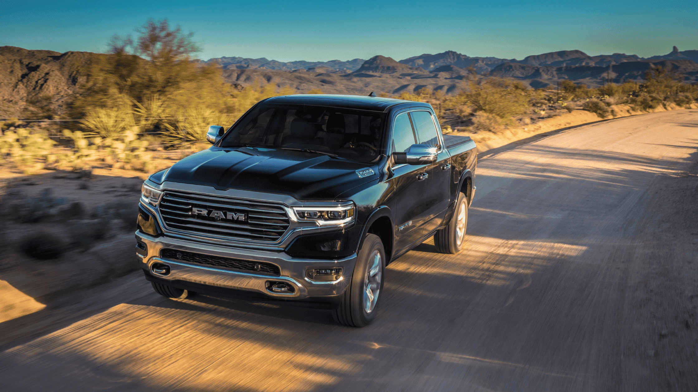 2024 Ram 1500 driving through desert landscape, showcasing rugged design.