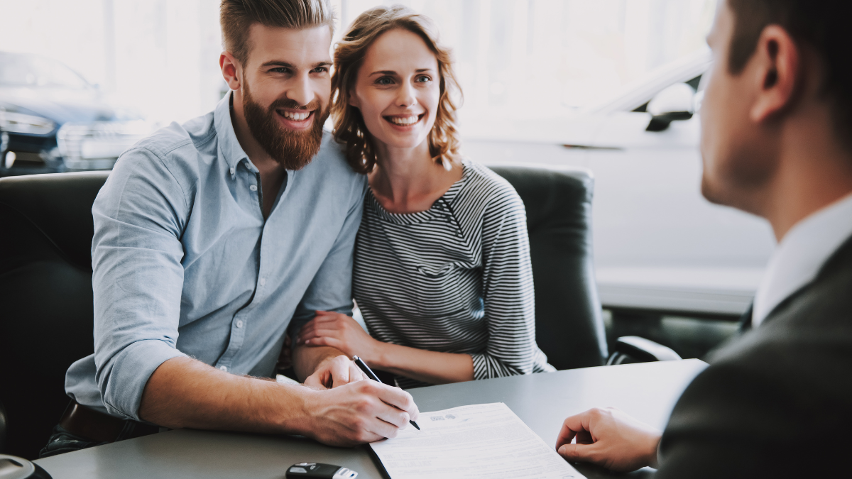 Smiling couple signing form to buy or lease a vehicle