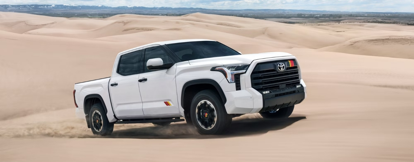 A white 2025 Toyota Tundra TRD Rally driving on sand.