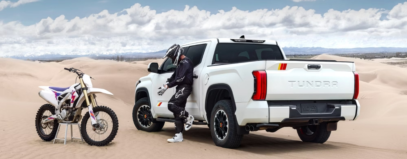 A white 2025 Toyota Tundra TRD Rally parked near a dirtbike.