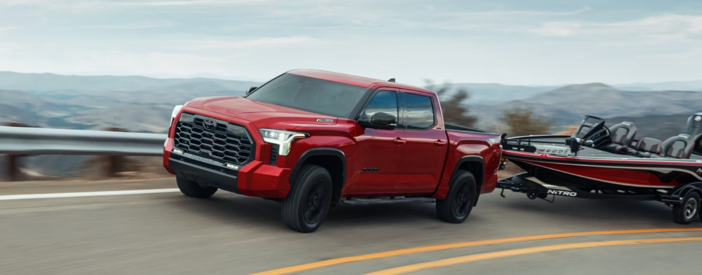A red 2025 Toyota Tundra for sale is towing a boat.