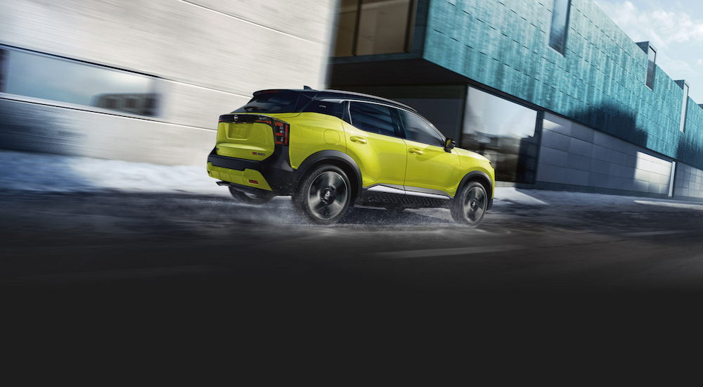 Rear view of a green 2025 Nissan Kicks driving in the rain.