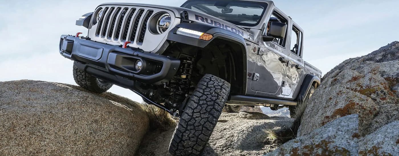 A grey 2023 Jeep Gladiator Rubicon is off-roading on a rocky trail.