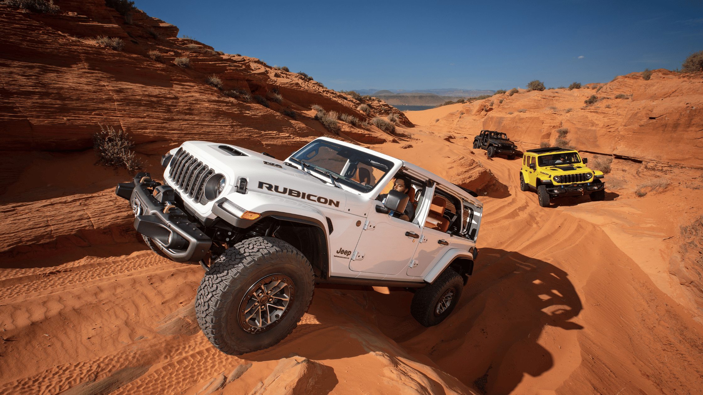 Jeep Wranglers off-roading through desert terrain.