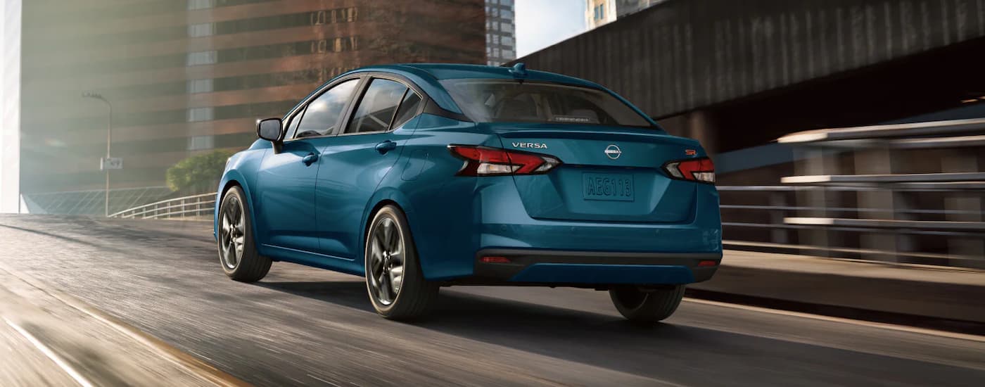 A blue 2025 Nissan Versa SR for sale is driving up a highway ramp.