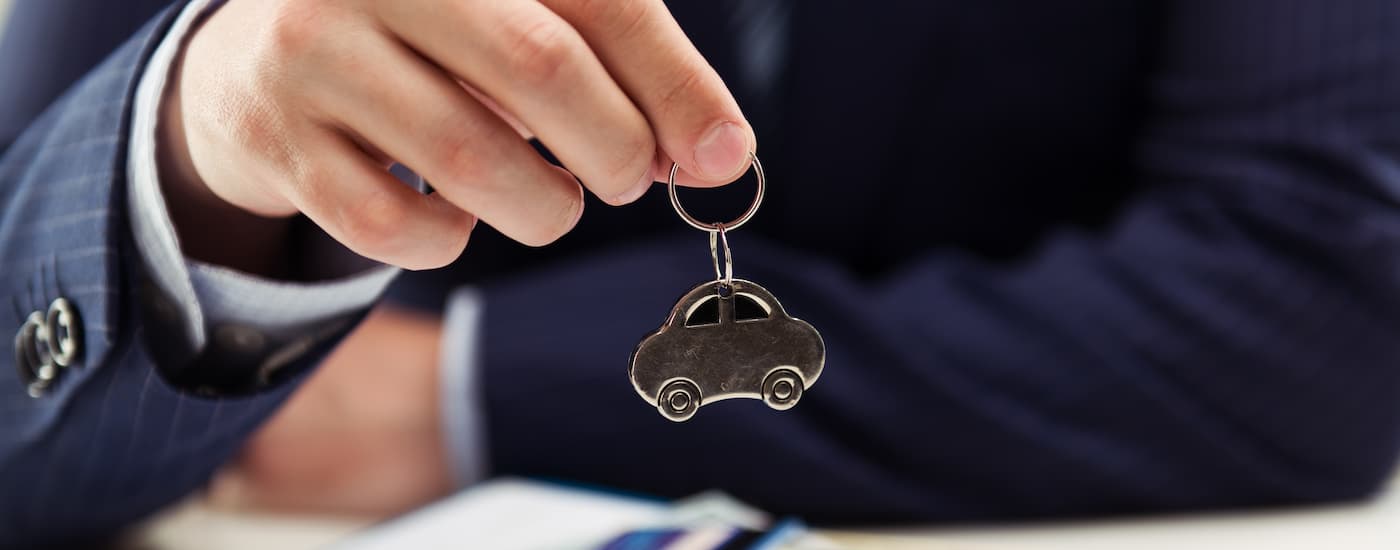 A salesman is holding up a car-shaped keychain.