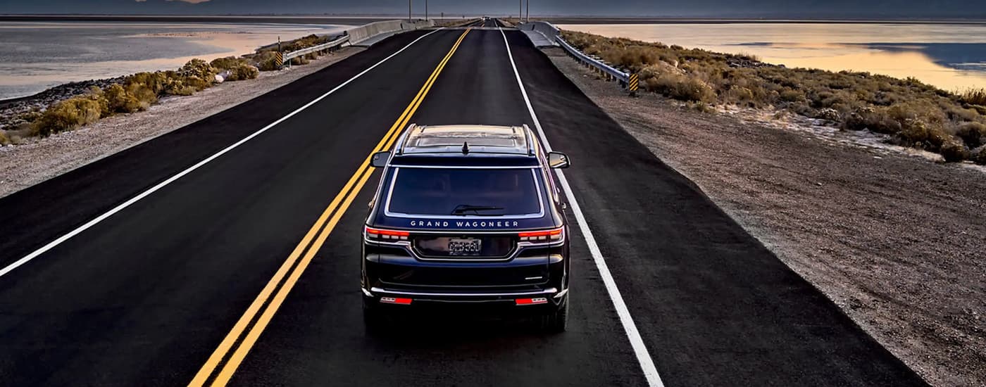 Rear overhead view of a black 2023 Jeep Grand Wagoneer driving to a Jeep dealer near Cinco Ranch.