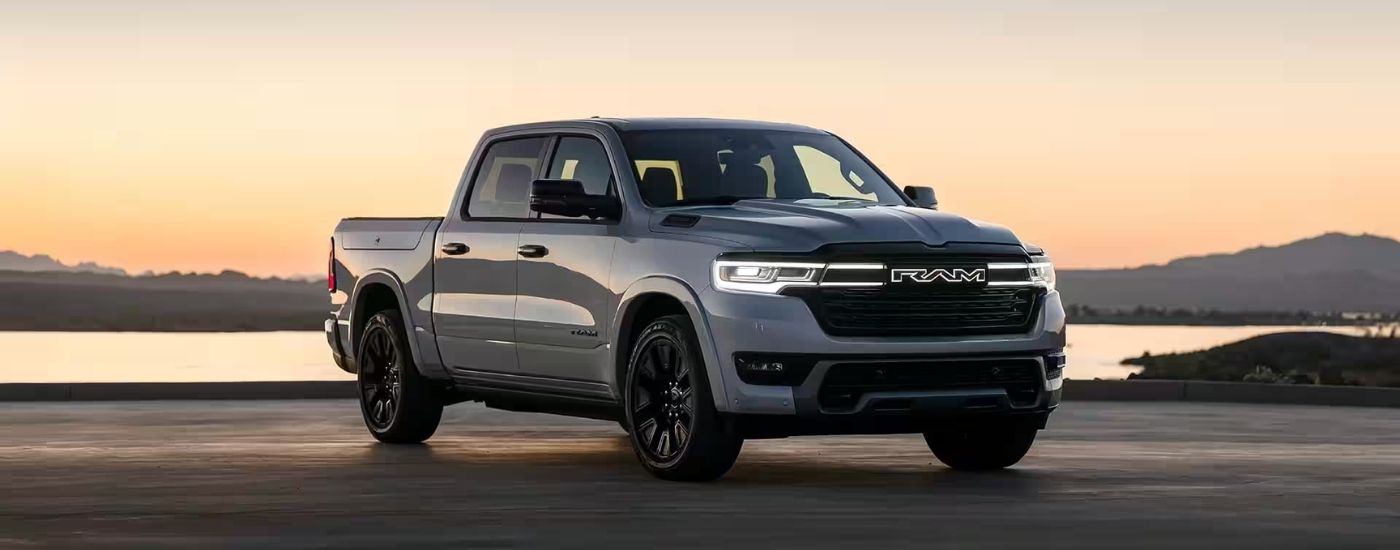 A grey 2025 Ramcharger parked by a lake at dusk after visiting a Ram dealer near Rosenberg.
