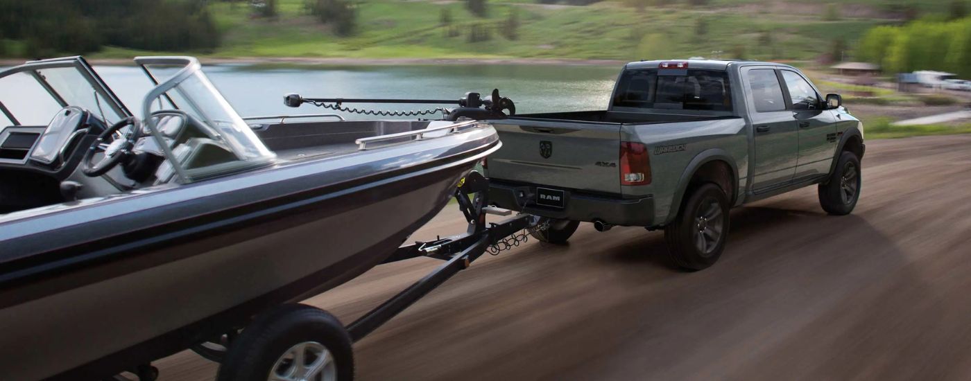 Rear view of a grey 2023 Ram 1500 Classic Warlock towing a boat.