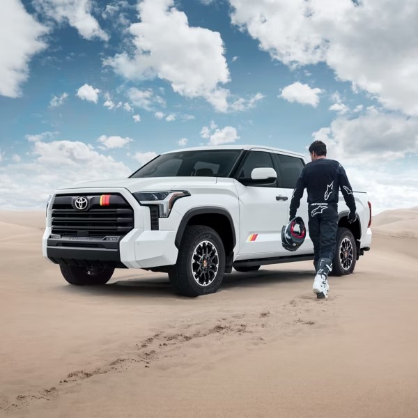 Man walking toward his new Toyota Tundra parked atop dune
