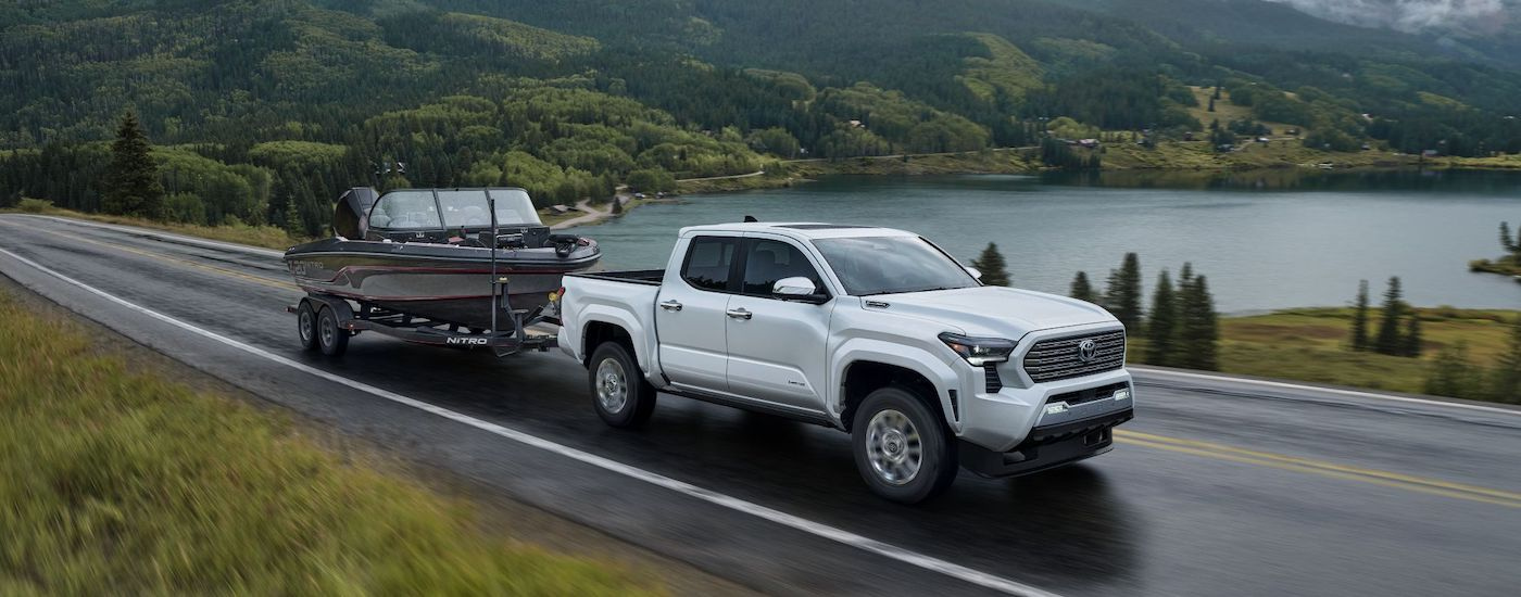 A white 2025 Toyota Tacoma for sale near me is shown towing a boat.