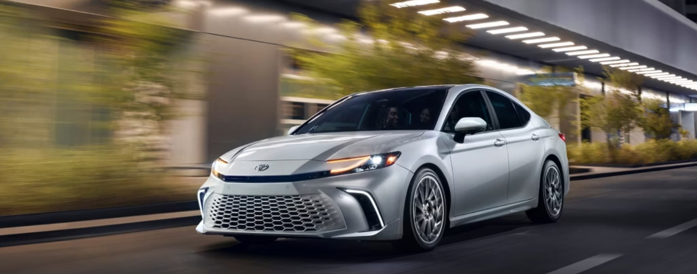 A white 2025 Toyota Camry is shown from the front at an angle.