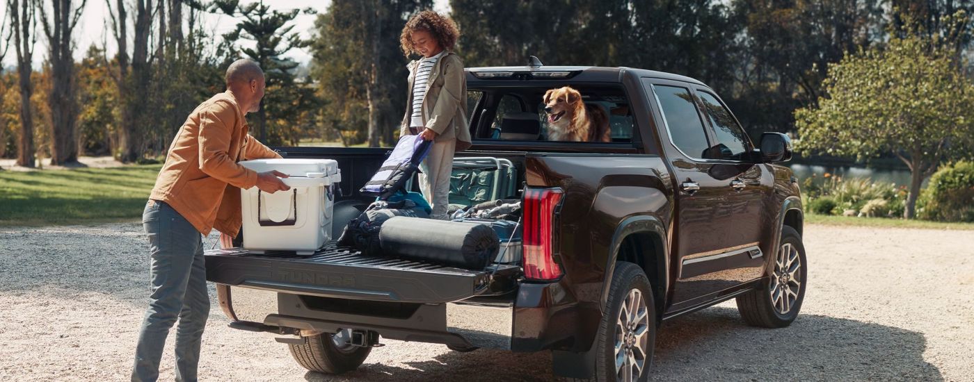 A father and daughter unloading camping gear from the bed of a black 2024 Toyota Tundra for sale in San Marcos.