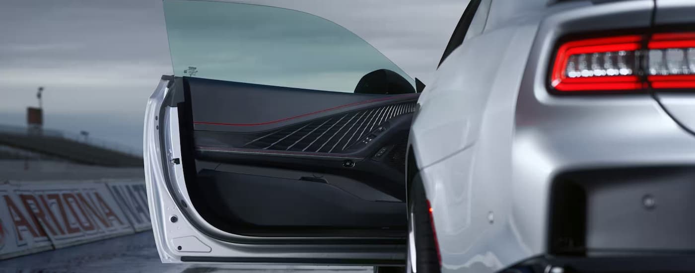 A rear view of a parked grey 2024 Dodge Charger Daytona R/T with the driver's side door open.