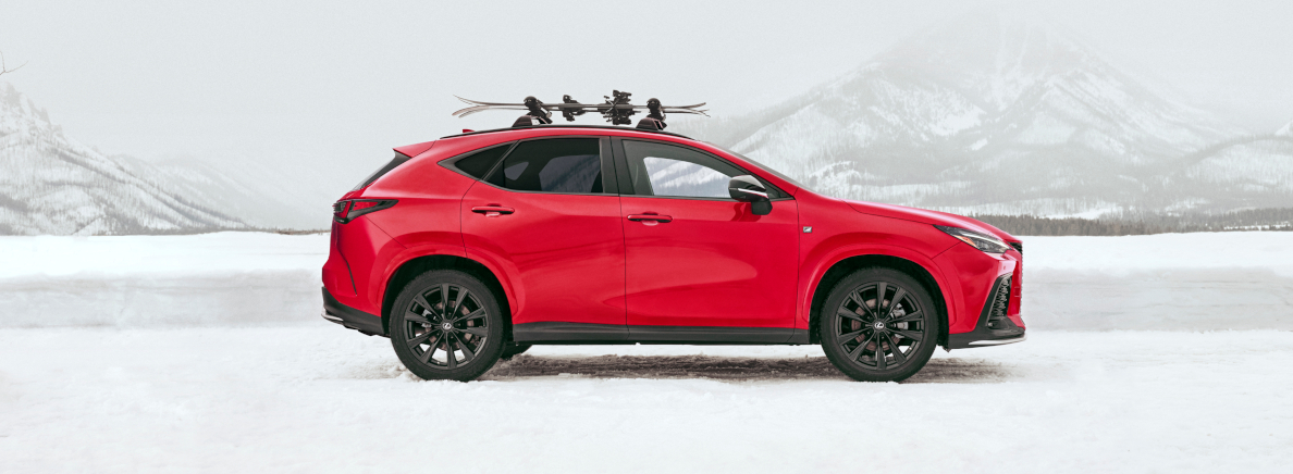 Image of a Lexus NX 350 driving in the snow in the mountains with snow skis on its luggage rack