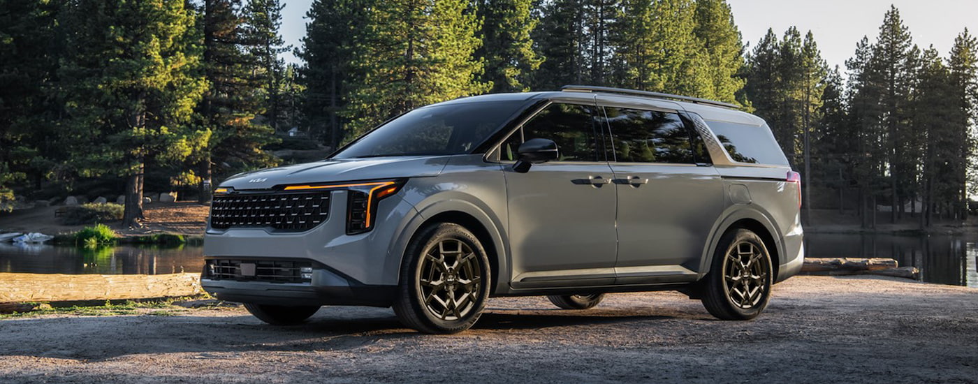 A grey 2025 Kia Carnival is shown from the side.