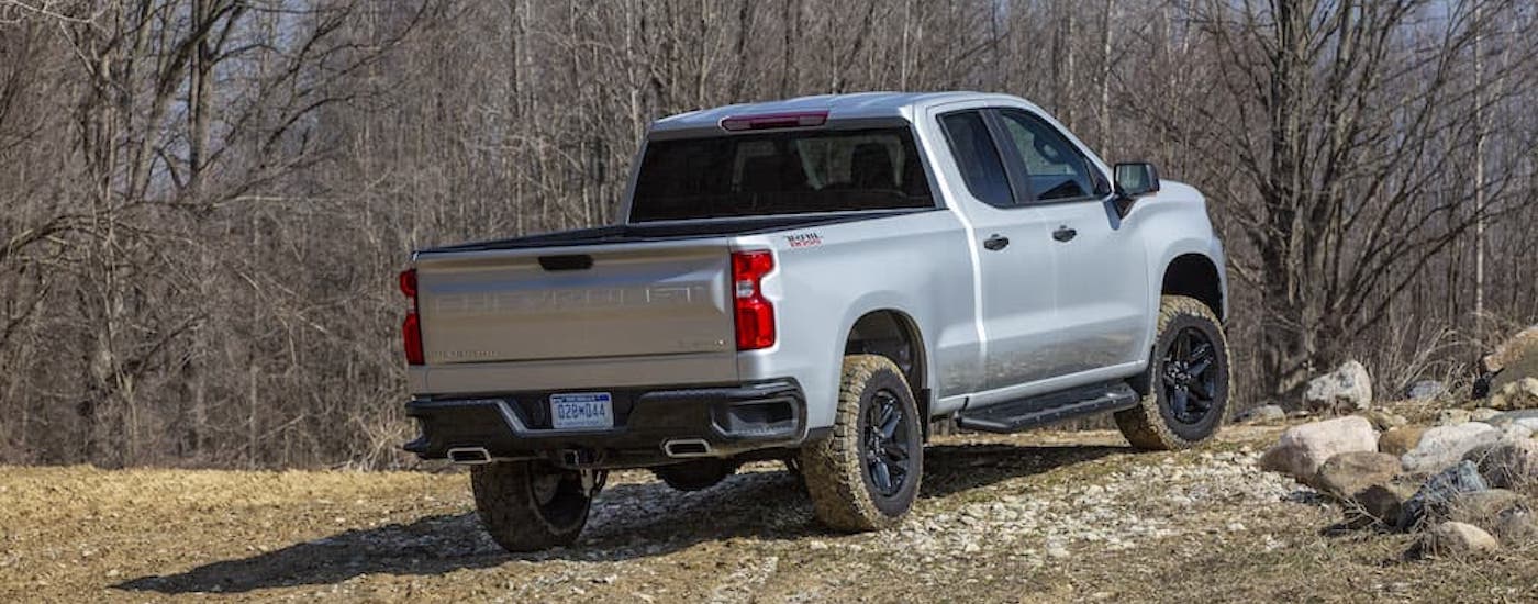 A silver 2025 Chevy Silverado 1500 LT Z71 Trail Boss is shown from the rear at an angle.