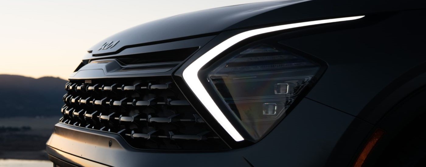 A close up of the headlight on a black 2023 Kia Sportage.