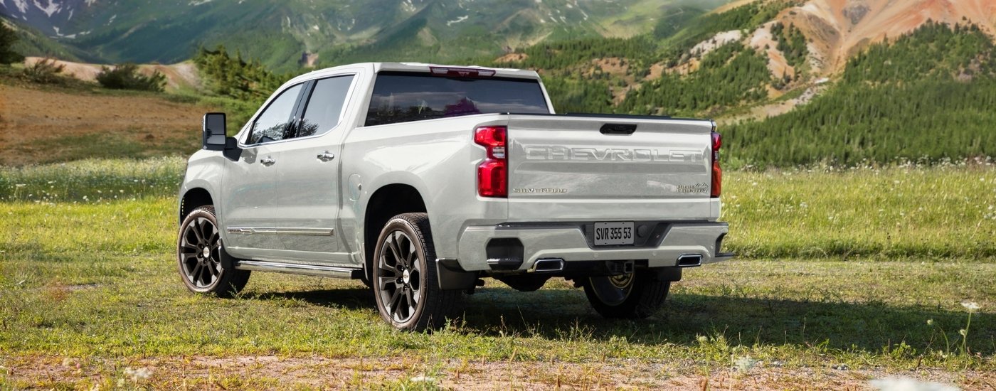 A white 2025 Chevy Silverado 1500 High Country is shown from the rear at an angle.