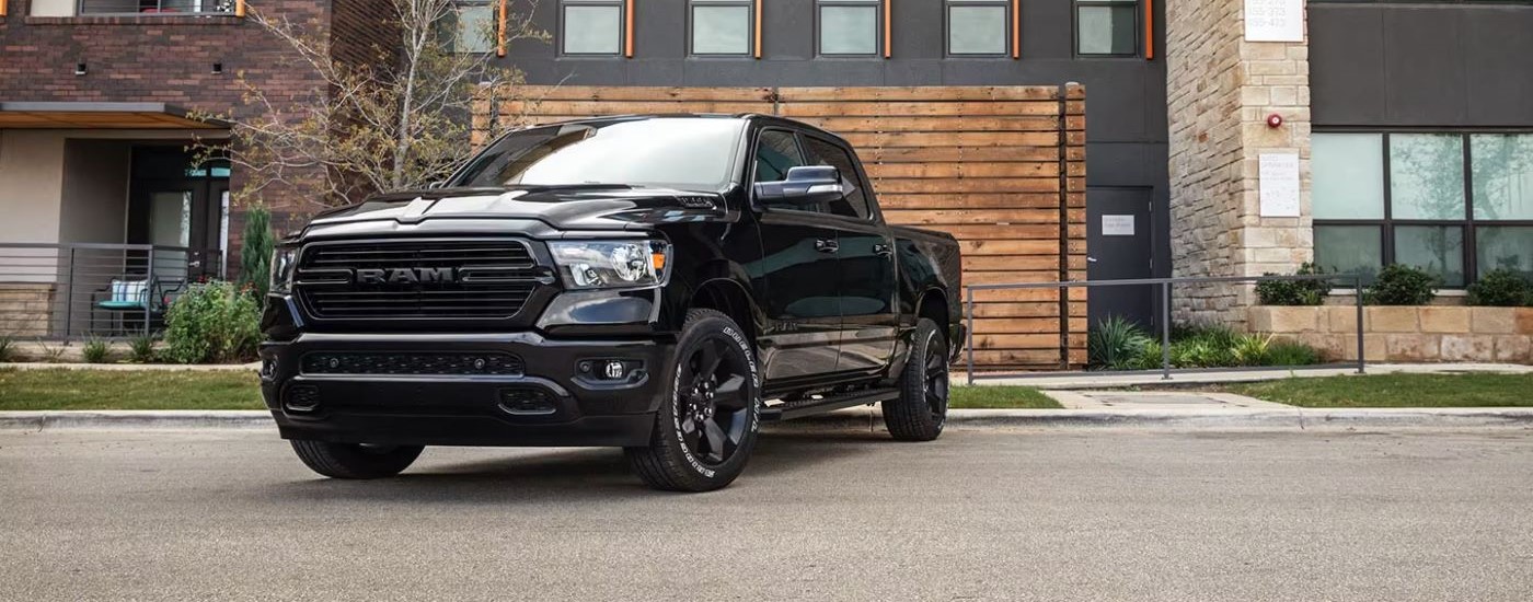 A black 2020 Ram 1500 for sale near Cypress is parked near a garage during a test drive,