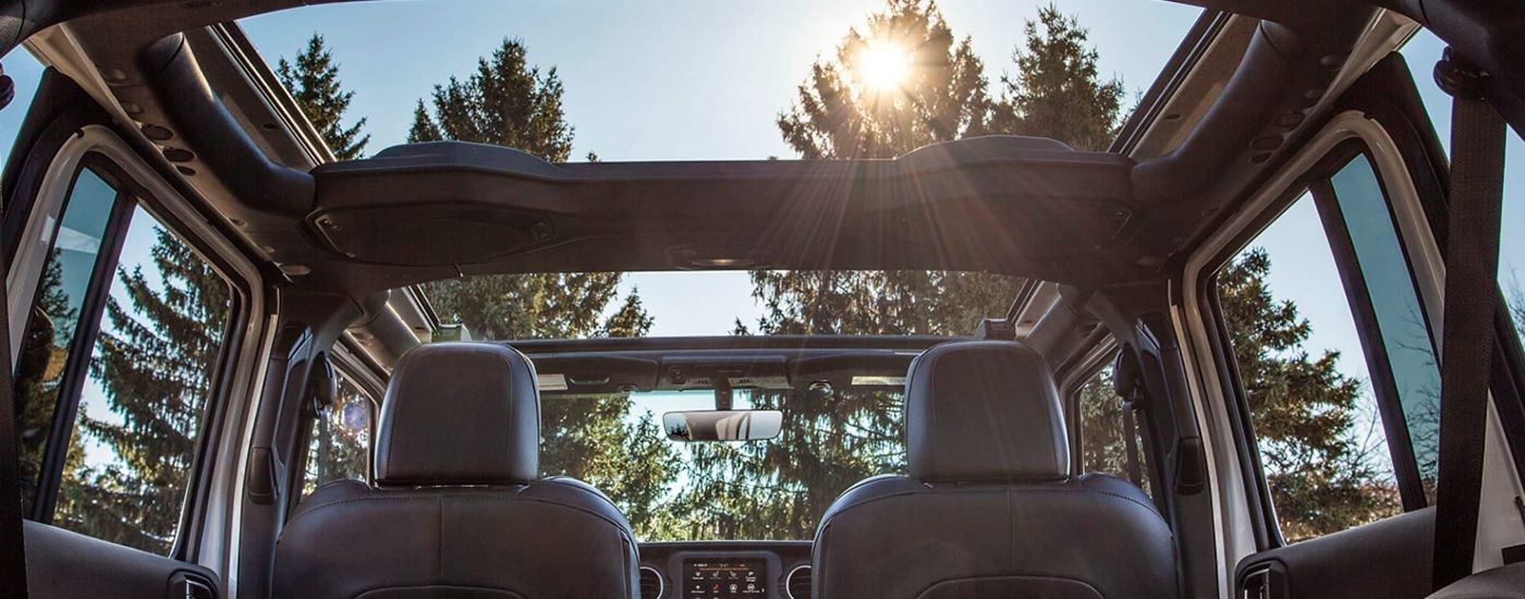 The front two seats and open roof in a 2023 Jeep Wrangler for sale near Tomball.