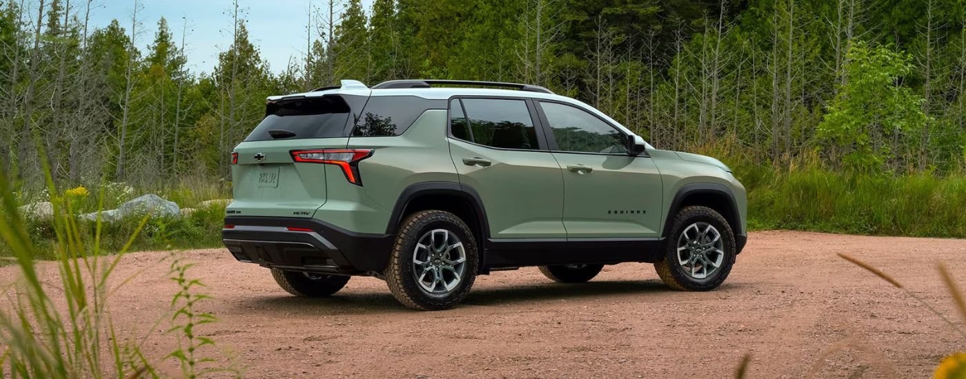 Rear view of a green 2025 Chevy Equinox ACTIV parked off-road.