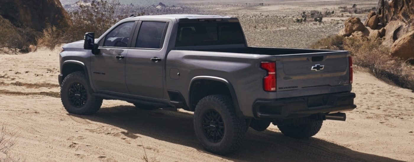 Rear view of a grey 2024 Chevy Silverado 2500 HD ZR2 parked on sand.