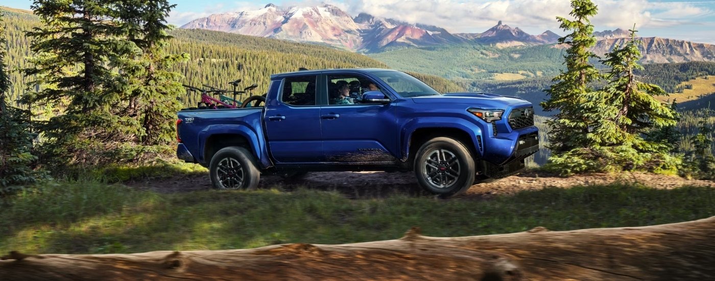 A blue 2025 Toyota Tacoma for sale is shown from the side.