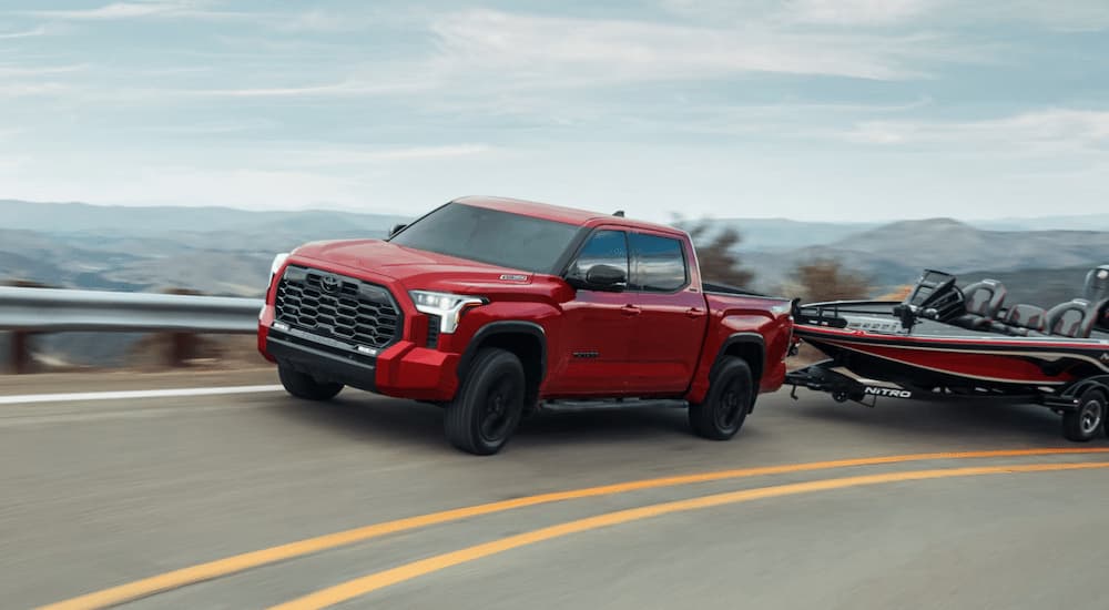 A red 2025 Toyota Tundra Limited Hybrid CrewMax is towing a fishing boat.