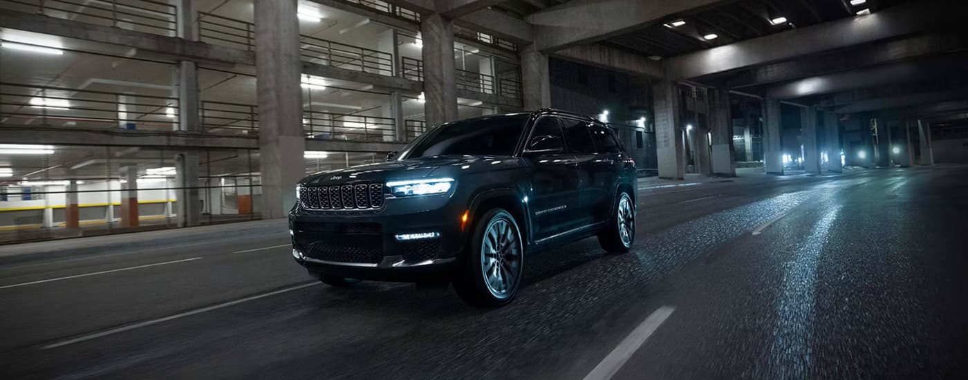 A black 2025 Jeep Grand Cherokee for sale driving in a city.