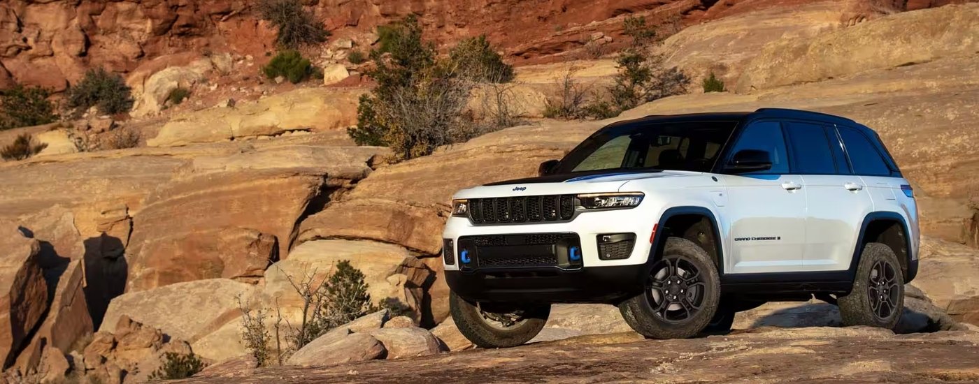 A white 2025 Jeep Grand Cherokee 4xe Trailhawk parked off-road.