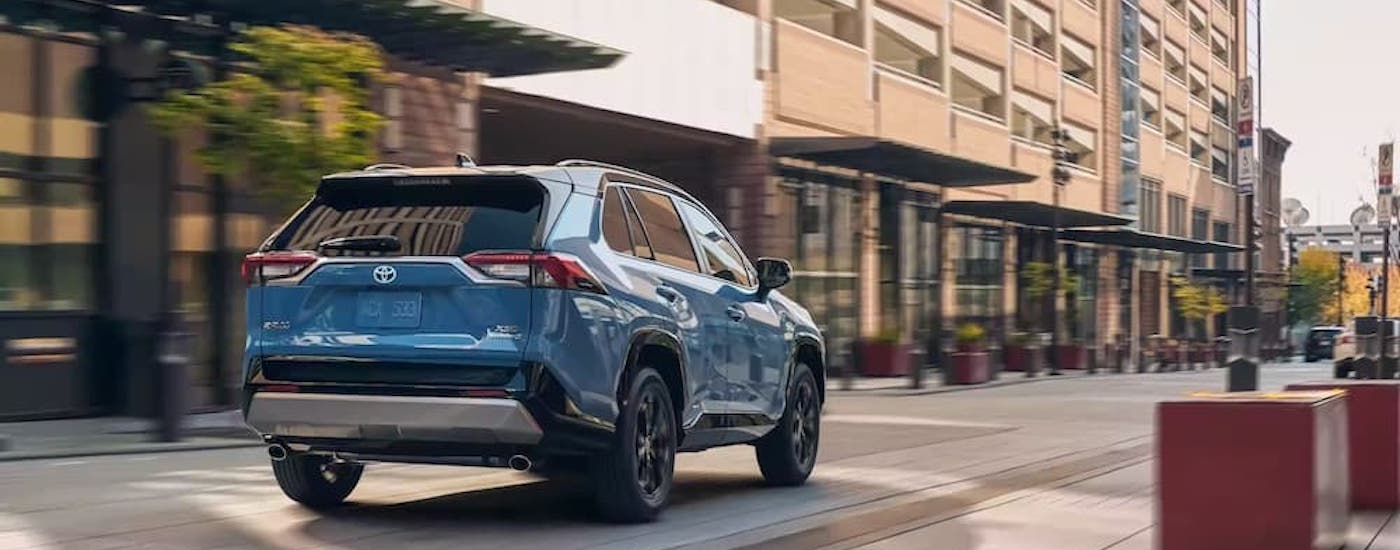 A blue 2025 Toyota RAV4 Hybrid XLE is shown from the rear at an angle.