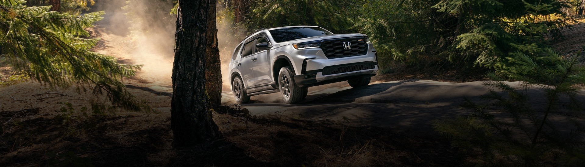2026 Honda Pilot driving through the woods