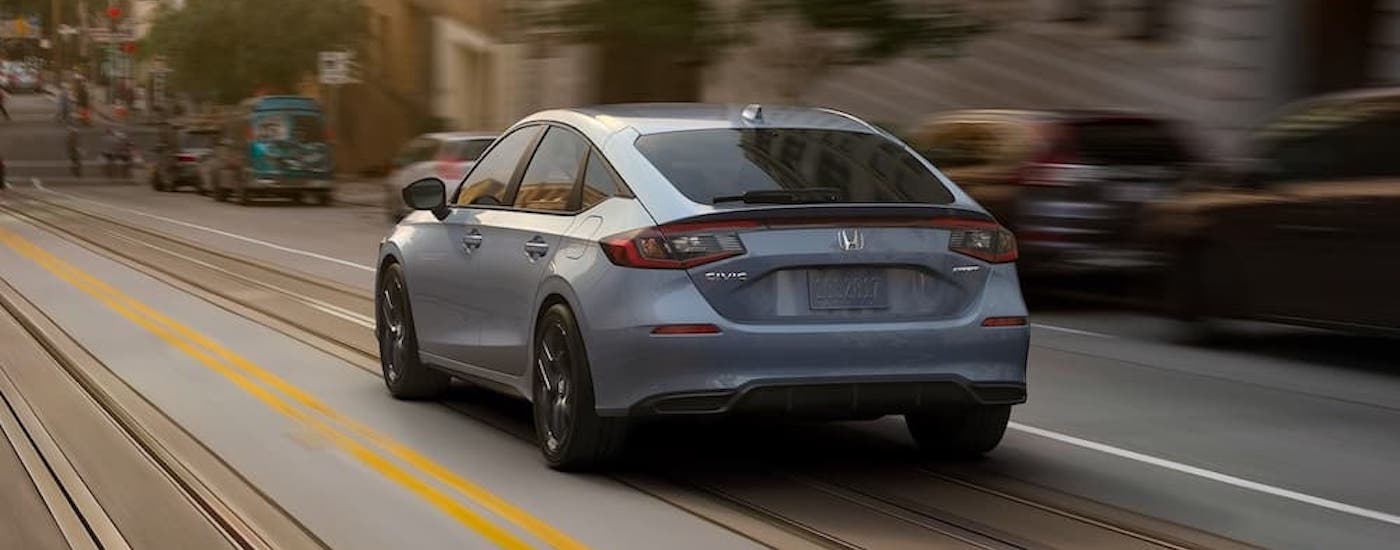 A grey 2023 Honda Civic driving in a city.