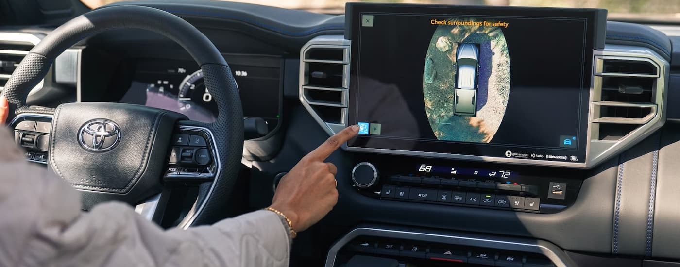 A man is using the infotainment screen in a 2025 Toyota Platinum CrewMax for sale.
