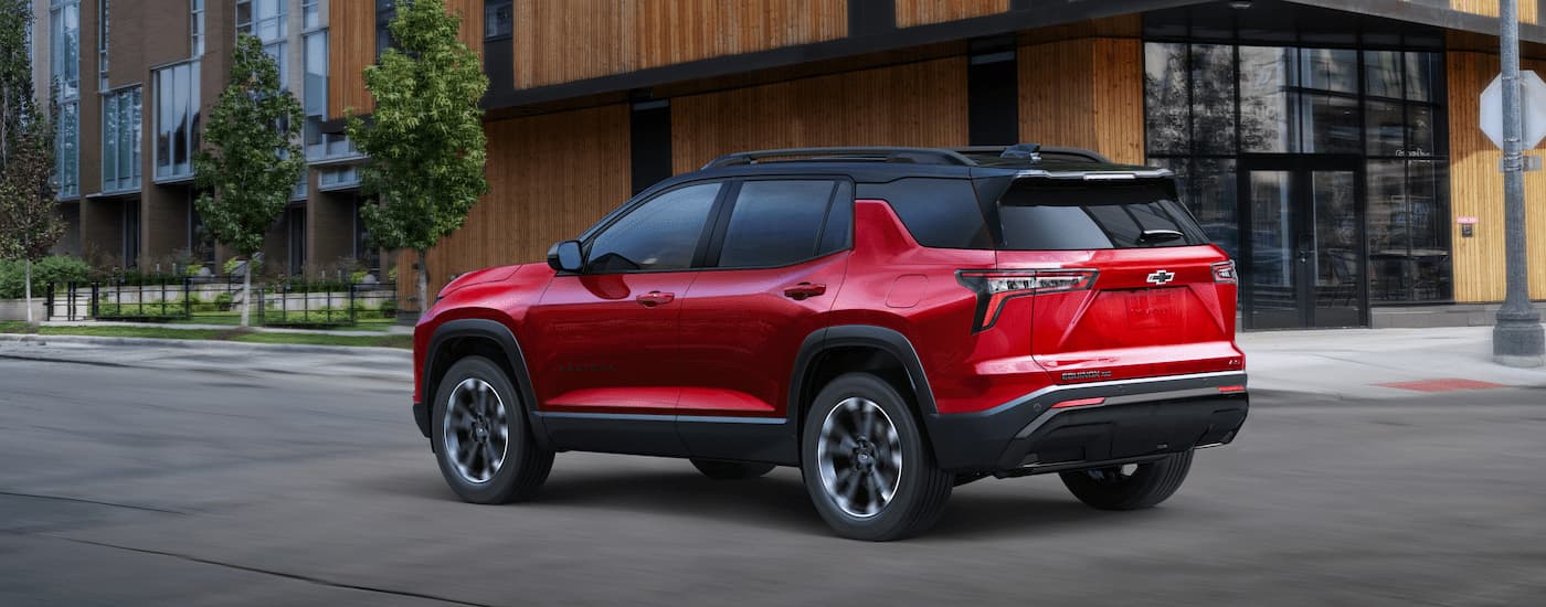 A red 2025 Chevy Equinox RS for sale driving on a city street.