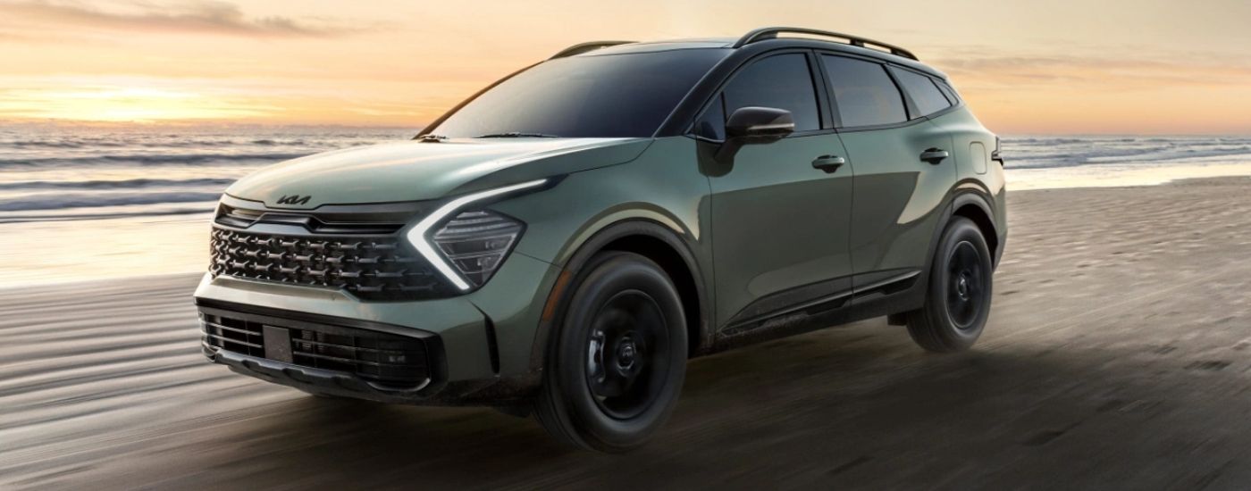 A green 2025 Kia Sportage X-Pro driving on a beach.